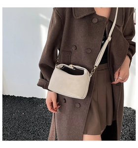 Detail view of cream white half-moon crossbody bag with gold metal hooks and adjustable strap