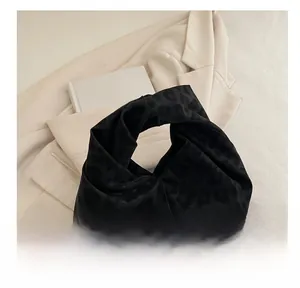 Detail view of leopard print handbag featuring a stylish knotted handle and pleated velvet texture