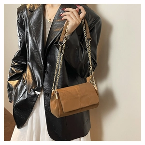 Close-up of brown quilted chain bag with matte texture on model in leather jacket