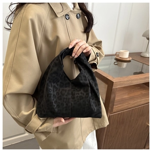 Détail d'un sac à main chic à motif léopard noir porté avec un trench-coat beige