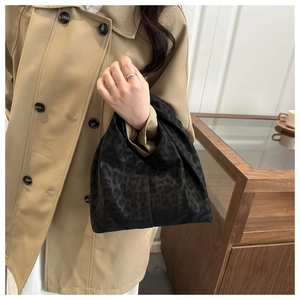 Detail of minimalist black leopard print tote bag paired with a khaki trench coat