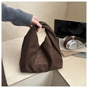 Detailed view of dark brown leopard embossed soft handbag with a unique twisted handle design