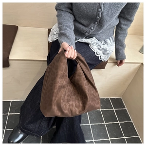 Chic leopard print faux suede tote bag shown in a stylish handheld lifestyle pose