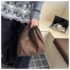 Sac hobo marron à imprimé léopard en tissu soyeux porté par un mannequin au bureau