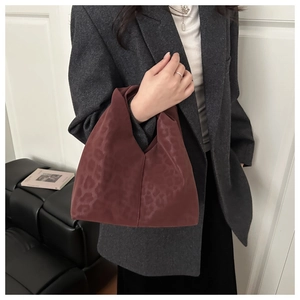 Detail shot of the luxury leopard print texture on a burgundy oversized cloud handbag