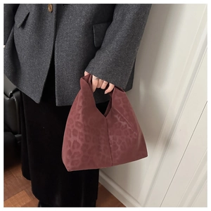 Close-up of burgundy leopard print cloud bag made of soft suede fabric in hand
