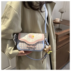 Detail of cartoon patchwork crossbody bag with 3D bow and cute bear keychain charm