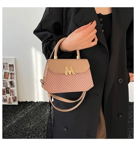 Detail of a beige and pink woven leather crossbody bag with a gold metal M logo