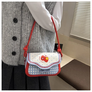 Detail of cartoon apple embroidery and bow decoration on red plaid crossbody bag