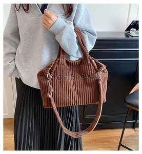 Detail of brown corduroy tote bag with black embroidery and adjustable shoulder strap