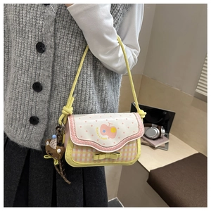 Detail of sweet pink and yellow checkered saddle bag with a cute bear plush charm