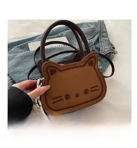 Close-up of brown cat-shaped saddle bag with embroidery detail and checkered scarf accessory