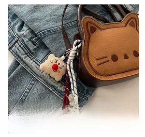 Close-up of cat-shaped brown suede handbag with embroidery and plush bear charm