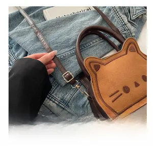 Detailed close-up of brown cat-themed bag with embroidery and adjustable gold buckle
