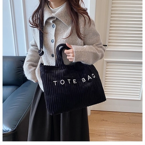 Detailed view of the black corduroy tote bag featuring white text and a versatile shoulder strap