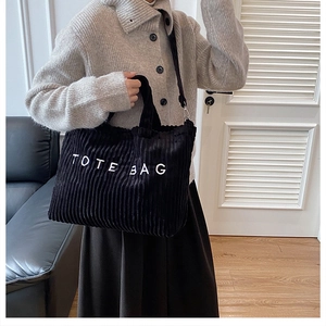 Detail van de zwarte corduroy draagtas met witte TOTE BAG tekst en afneembare schouderriem