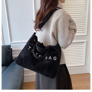 Detail of black corduroy tote bag with TOTE BAG embroidery and adjustable shoulder strap