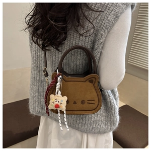 Vue détaillée du sac selle chat en daim marron avec un pendentif bonhomme de pain d'épices