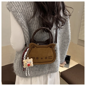 Détail d'un sac selle en forme de chat avec charm en peluche et texture daim