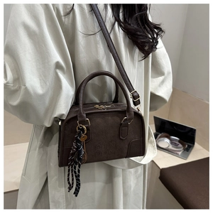 Dettaglio della borsa Boston marrone con goffratura QTN e ciondolo a corda a righe