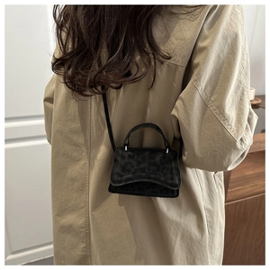 Dettaglio della mini borsa nera con stampa leopardata indossata con un trench coat beige