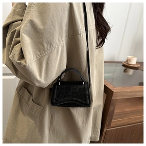 Dettaglio mini borsa nera con trama leopardata e design con base curva unica