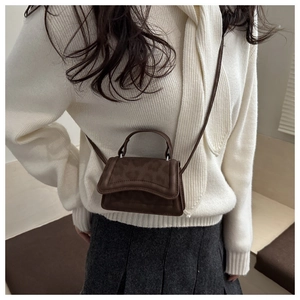 Dettaglio di una mini borsa leopardata marrone scuro indossata da una modella di moda