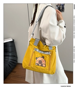 Detail view of the yellow crossbody bag featuring a cute cartoon patch and lettered straps