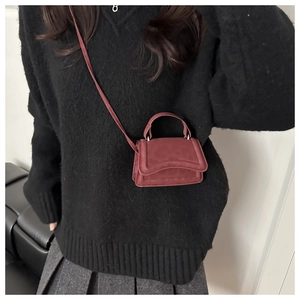 Vista a tracolla di una mini borsa quadrata bordeaux con texture opaca e manico superiore