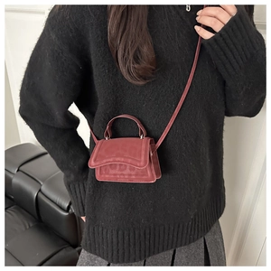 Dettaglio mini borsa a tracolla bordeaux in finto scamosciato su maglione nero