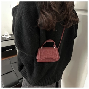 Dettaglio della borsa a tracolla bordeaux con trama animalier su modella con maglione