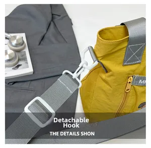 Detail of yellow nylon tote showing gray strap and white detachable plastic hook