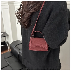 Dettaglio della mini borsa bordeaux in pelle opaca con base curva e sottile tracolla