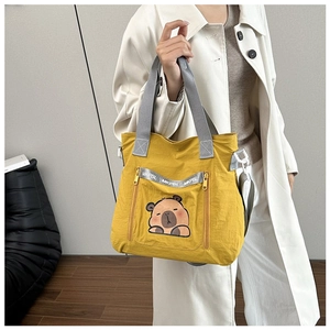 Detail of yellow canvas tote bag featuring cute capybara print and side zipper pocket