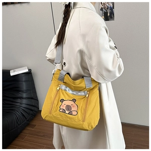 Detail of yellow cartoon canvas tote with dual zipper pockets and logo strap detail