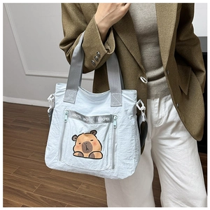 Detail of light blue nylon tote bag with cute cartoon capybara embroidery and gray handles