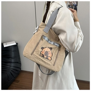 Detail of khaki canvas tote bag with capybara print and MKPBL lettered shoulder strap