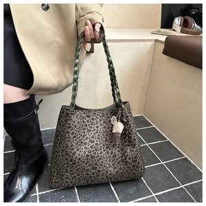 Dettaglio della borsa tote leopardata con manico intrecciato verde e ciondolo di peluche