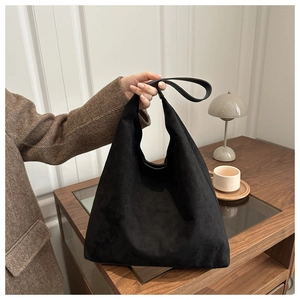 Dettaglio borsa hobo vintage in pelle scamosciata nera con tracolla larga su legno