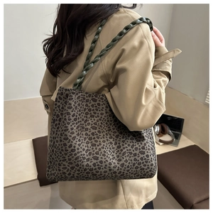Dettaglio della borsa tote leopardata con tracolla in pelle intrecciata verde scuro e modella