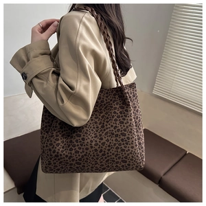Vista dettagliata della borsa tote leopardata con manici intrecciati su una modella