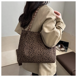 Dettaglio di una borsa tote grande con stampa leopardata e manici intrecciati marroni