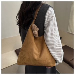 Borsa tote in velluto marrone indossata da modella con ciondolo a forma di orsetto