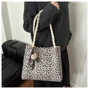 Dettaglio della borsa tote leopardata con manici intrecciati e ciondolo in peluche