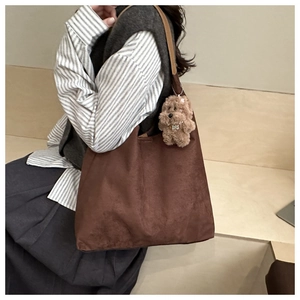 Dettaglio borsa tote in pelle scamosciata marrone con ciondolo a forma di orsetto peluche