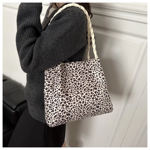 Dettaglio della borsa tote leopardata con manico in corda intrecciata indossata da una modella
