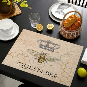 Detailed view of vintage linen placemat with bee and crown pattern on a dark table