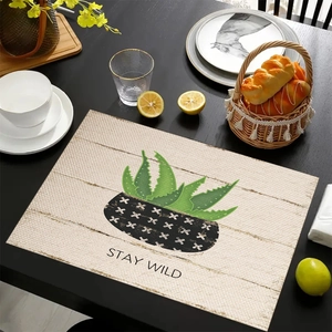 Linen placemat with green aloe plant print and Stay Wild text on dark wooden table