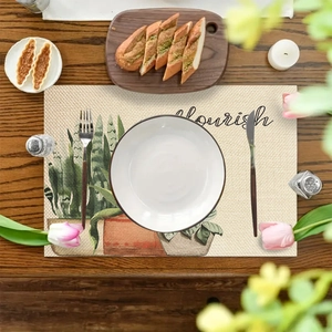 Linen placemat with green plant print and 'flourish' text on a dark wood table
