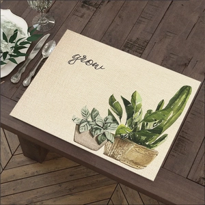 Linen dining placemat with green plant print and Grow text on dark wood tabletop
